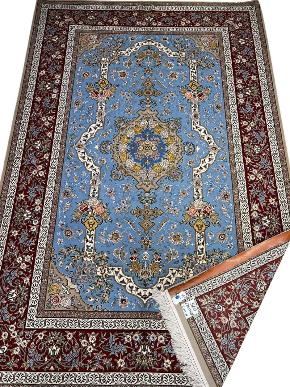 "Hand-knotted Persian Isfahan rug with a light blue floral field and burgundy border, crafted by Mansourie."